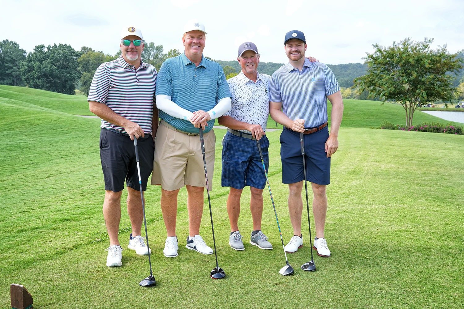 four golfers standing on the green with their golf clubs